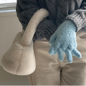 Detalle de bolso de peluche blanco y guantes azules claro en una toma de estilo invernal
