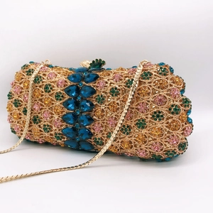 Detail of hollow evening bag with floral rhinestones and dark blue gemstones with gold chain