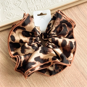 Detailed view of leopard print scrunchie with satin texture and neat brown stitched edges