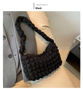 Close-up of black bubble textured fabric shoulder bag with gold zipper detail