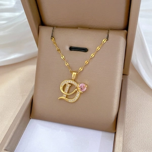 Detail of gold D-letter pendant with pink and clear cubic zirconia on white silk