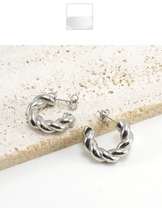 Detailed view of silver twisted croissant earrings on a natural white textured stone