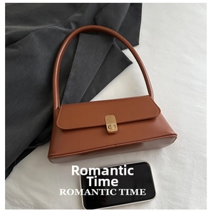 Brown leather baguette bag with gold metal buckle shown next to a smartphone for scale