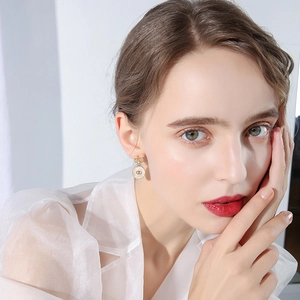 Detailed close-up of gold dangle earrings with white enamel and double-C logo design