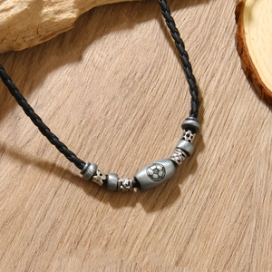 Retro faux leather football pendant necklace with metallic beads on wooden background