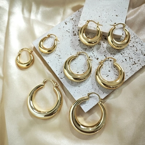 Minimalist 18K gold plated hoop earrings in various sizes on a textured stone surface