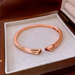 Bracelet jonc ouvert en or rose avec motifs de coquillages sur boîte à bijoux en lin