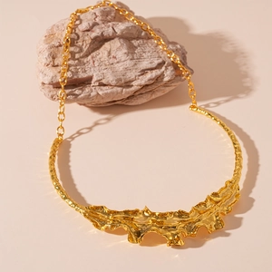 Detail shot of a golden metal choker featuring unique liquid lava sculptural texture