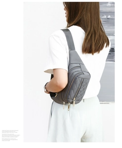 Gray quilted fanny pack with gold zippers shown worn as a crossbody chest bag