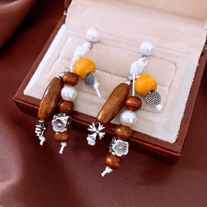 Macro detail of bohemian earrings featuring wood beads and pearls in a jewelry box