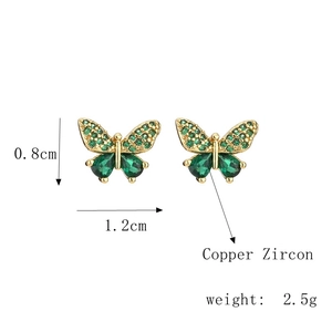 Detail of butterfly stud earrings featuring green zircon wings and copper gold finish