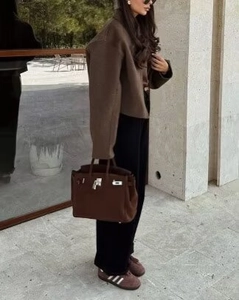 Veste courte en laine marron portée par un mannequin avec pantalon noir et sac à main