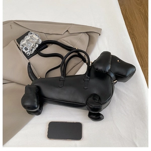 Creative dachshund-shaped black leather handbag displayed with office attire and accessories