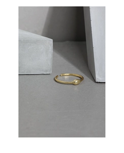 Makro-Detail eines matten Goldrings in Tropfenform auf grauem Industrieblock