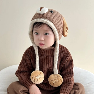 Close-up of baby knit hat featuring puppy dog ears and plush bone pendants with Baby text