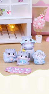 Close-up of four mini resin cat figurines in various cute outfits on a desk