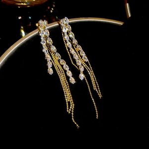 Macro detail of gold long tassel earrings with sparkling marquise cut crystals