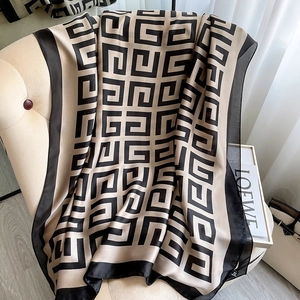 Elegant beige and black houndstooth pattern scarf draped over a chair in soft natural light