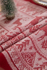 Close-up of red and white woven Christmas table runner with reindeer and tree patterns