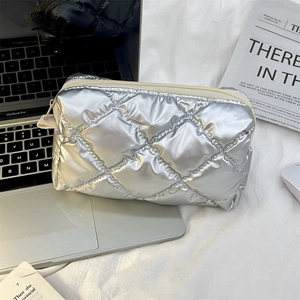 Detail of silver quilted makeup bag with metallic finish and top zipper closure