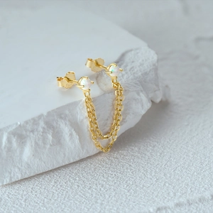 Macro view of S925 sterling silver opal double piercing chain earrings with gold finish
