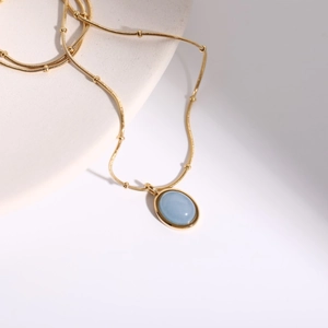 Detail of 18K gold plated necklace featuring a light blue natural stone oval pendant