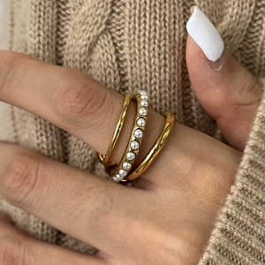 Macro shot of 18K gold plated triple-layer ring with white pearls on a knit sweater