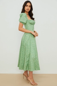 Detail of green floral midi dress featuring puff sleeves and a side slit for a retro look