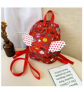 Detail of red toddler backpack with rainbow prints and white polka dot wing accents