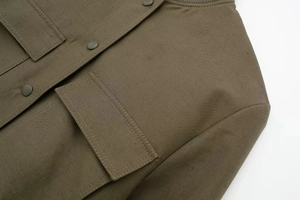 Detailed close-up of olive green cargo jacket showing premium stitching and snap pockets