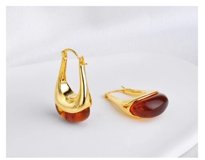 Detailed macro view of U-shaped amber resin earrings with gold-plated metal finish