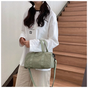 Detail of light green nylon Boston bag with double handles and adjustable strap