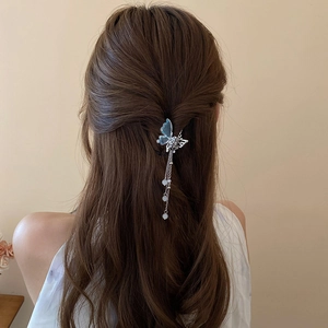 Détail de la pince à cheveux papillon avec franges perlées sur une coiffure mi-haute