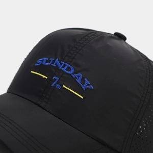 Macro view showing blue SUNDAY embroidery and breathable mesh on black quick-dry baseball cap