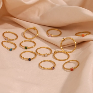 Set of 18K gold plated stainless steel birthstone rings on champagne silk background