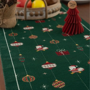 Detail of green woven Christmas table runner with Santa Claus and snowflake patterns
