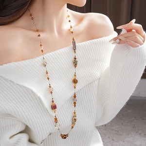 Détail d'un long collier en céramique marron avec pendentifs papillon et géométriques