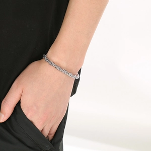 Détail d'un bracelet chaîne en corde torsadée argentée porté sur la main au style vintage
