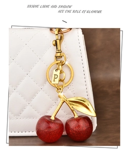 Close-up of cherry keychain with letter P charm on a quilted white handbag