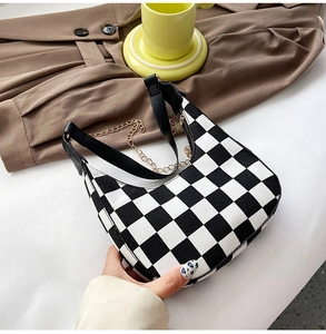 Detail shot of the black and white checkerboard canvas bag with gold chain and strap