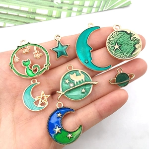Detail of DIY enamel cat and moon jewelry charms with blue and green gold-edged finish