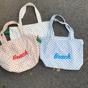 Detailansicht von Canvas-Einkaufstaschen mit Punkten und Beach-Aufdruck auf Asphaltboden