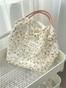 Close-up of floral canvas tote bag with woven handles on a white storage trolley