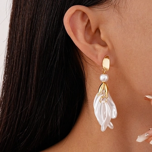 Gros plan de boucles d'oreilles pendantes en pétales de fleurs avec perle blanche