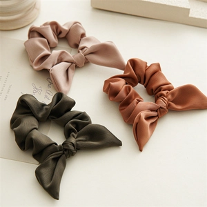 Three bow elastic hair scrunchies in pink, brown, and green textured fabric styles