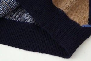 Close-up of navy blue diamond pattern knit and elastic ribbed hem on the sweater