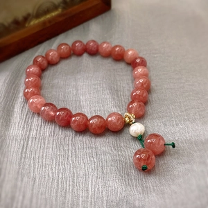 Macro view of strawberry quartz beads and white baroque pearl on elegant silk background