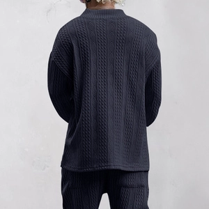 Close-up of the intricate cable knit texture on dark blue long sleeve knitted top