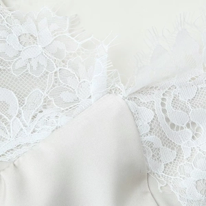 White satin slip dress with intricate lace stitching and silky texture close-up detail