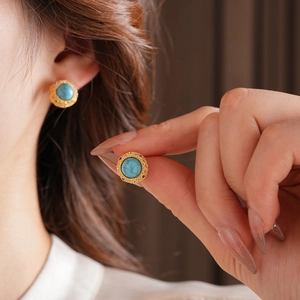 Close-up of vintage 18k gold plated turquoise stud earrings on a model's ear
